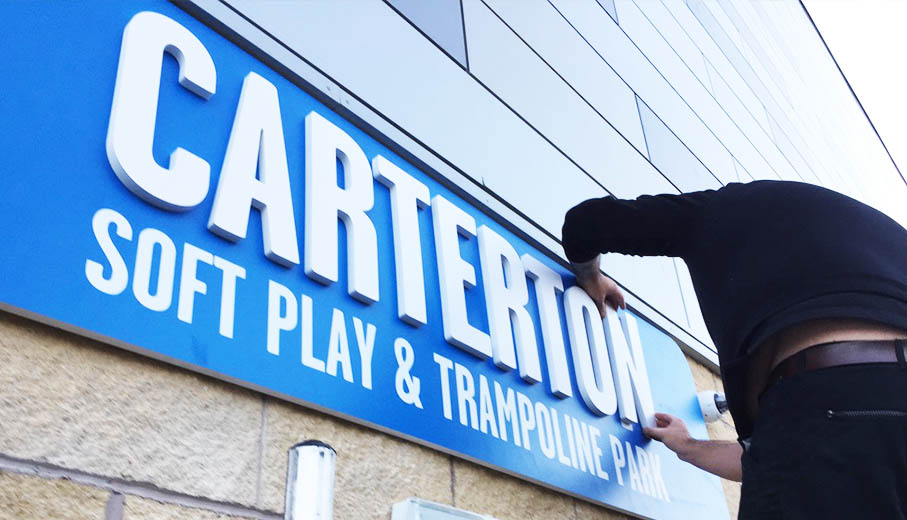 Fitting team member Rich, applying the final details to the external entrance signage at Carterton